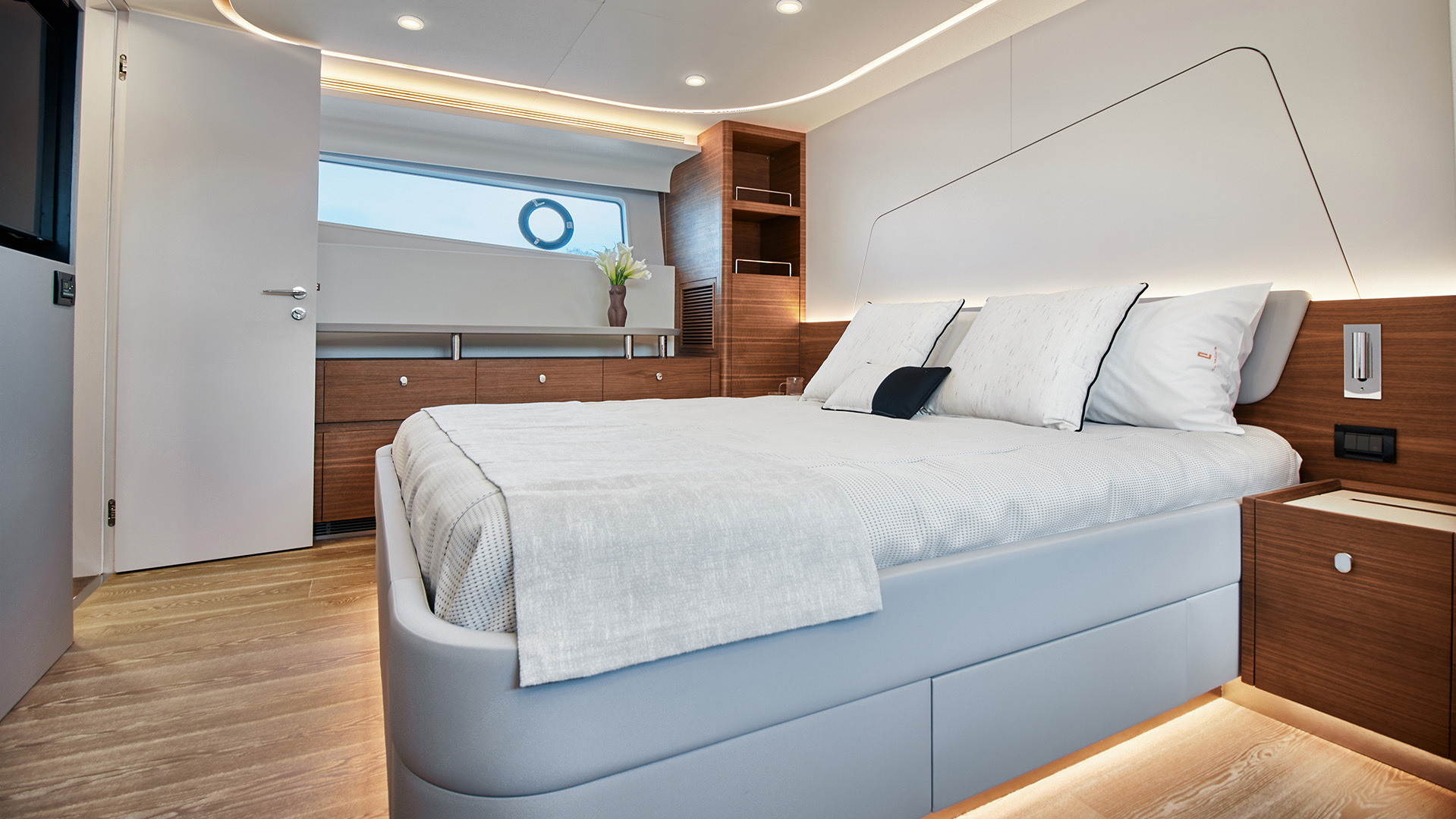 Yacht cabin with a double bed, wood furniture and a window to the outside