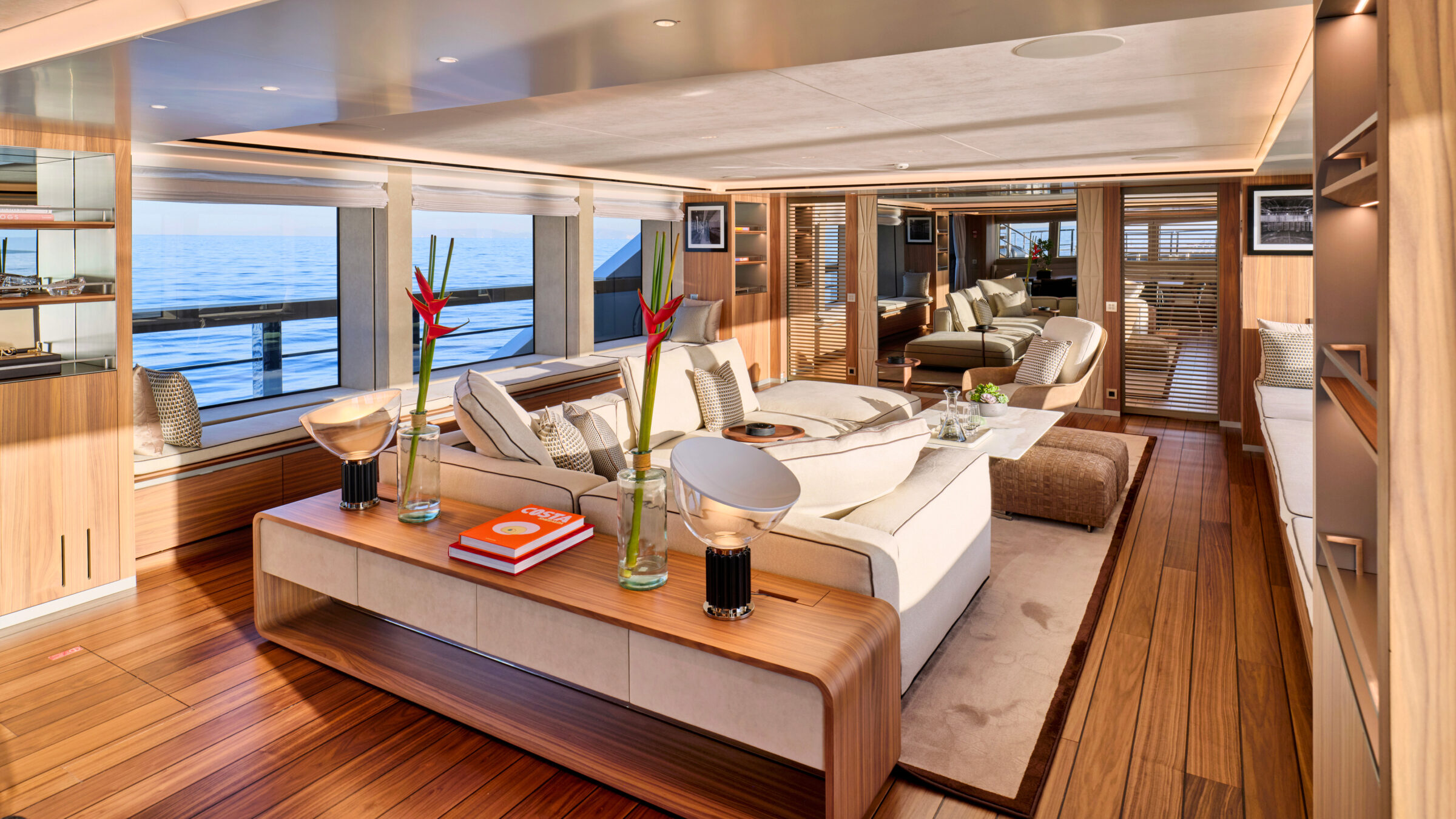 Main salon of a superyacht with light sofas, wood and windows to the sea
