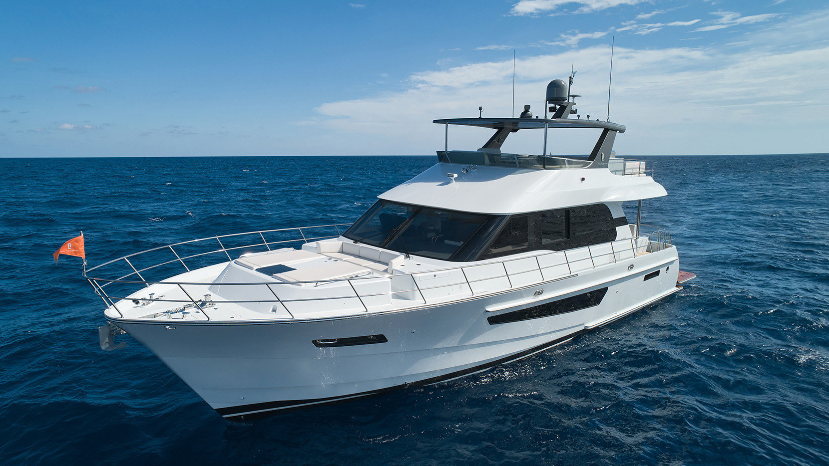White flybridge yacht at rest in open sea under a clear sky